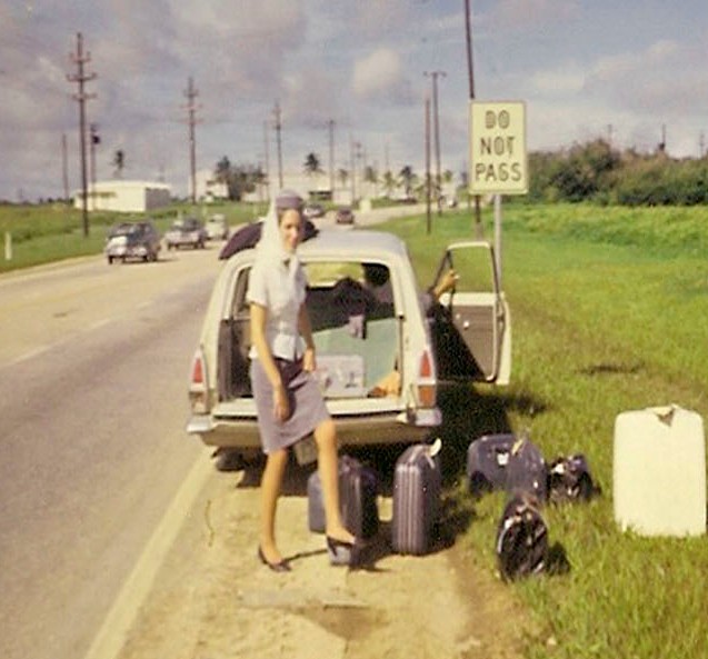 1960s Guam,  A flat tire on the crew car while en route to the airport.  The Flight Attendants begin to remove their luggage to access the spare tire.